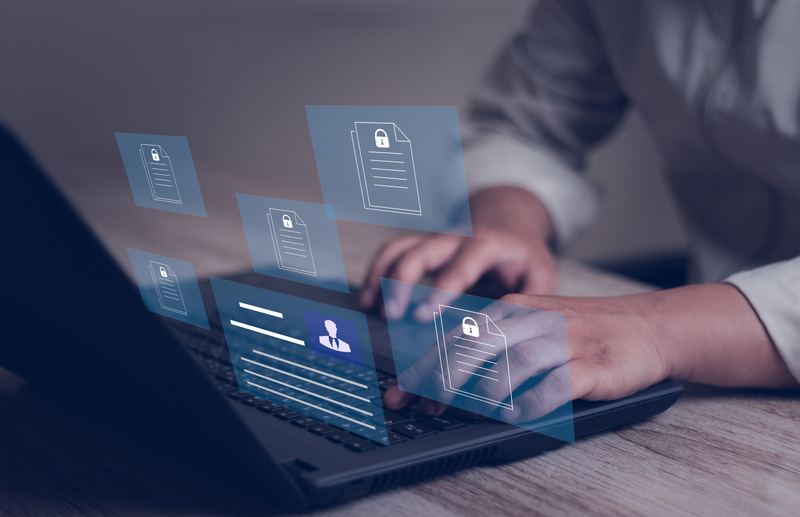 Person using a laptop with secure candidate documents displayed above the keyboard