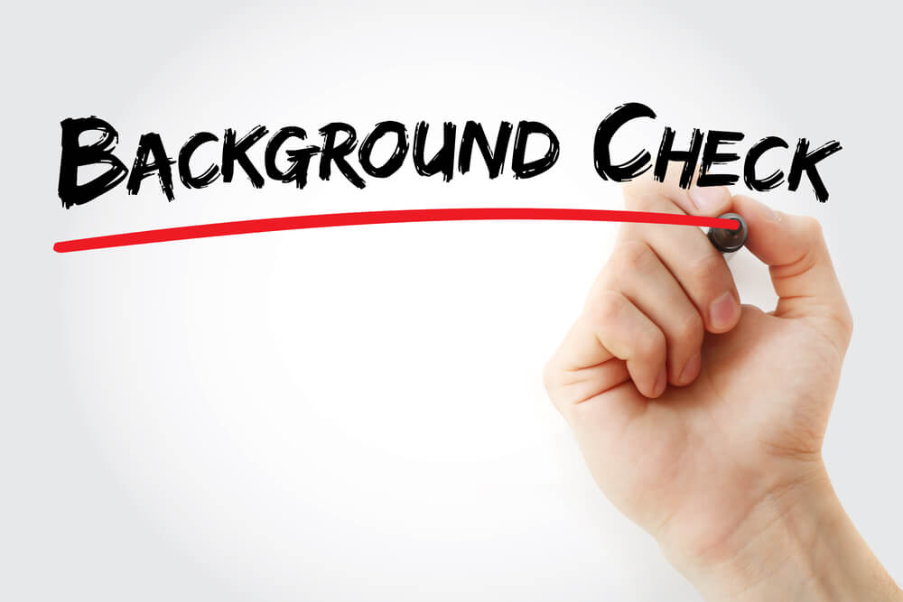 Image of someone writing 'background check' on a whiteboard in black ink.